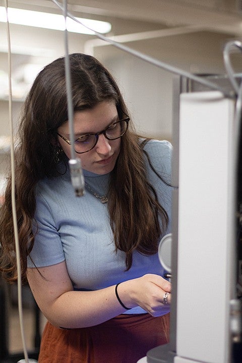 student in the lab bent over equipment