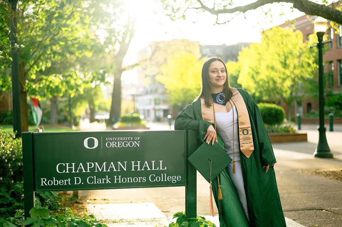 amiya fulton's graduation portrait standing in regalia next to Chapman Hall sign