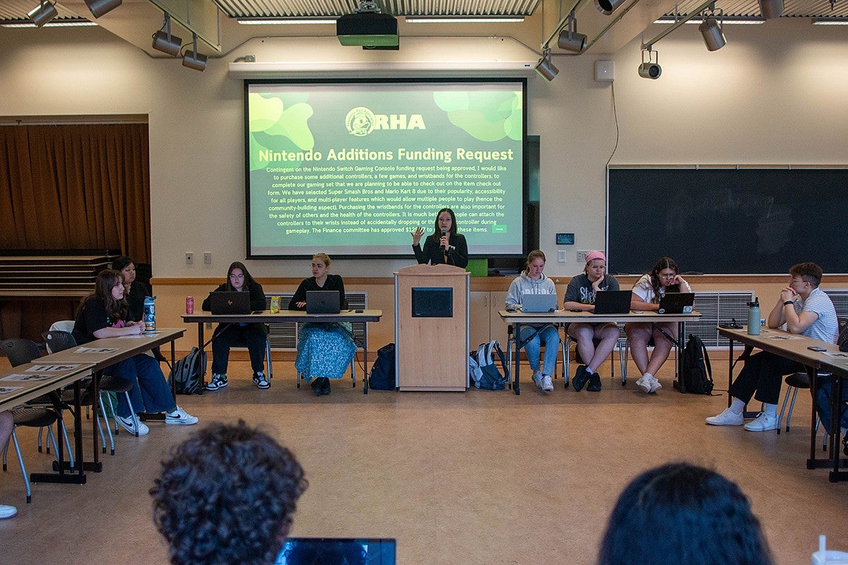 student leading a meeting and giving a presentation at front of seminar room