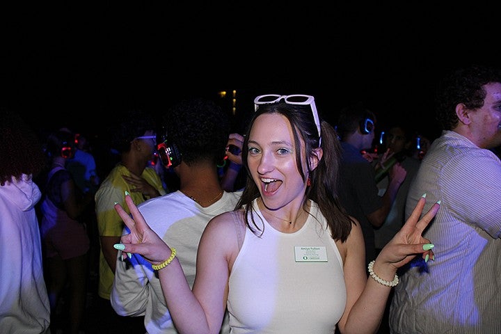 student posing at a silent disco in a dark room, lit by a flash
