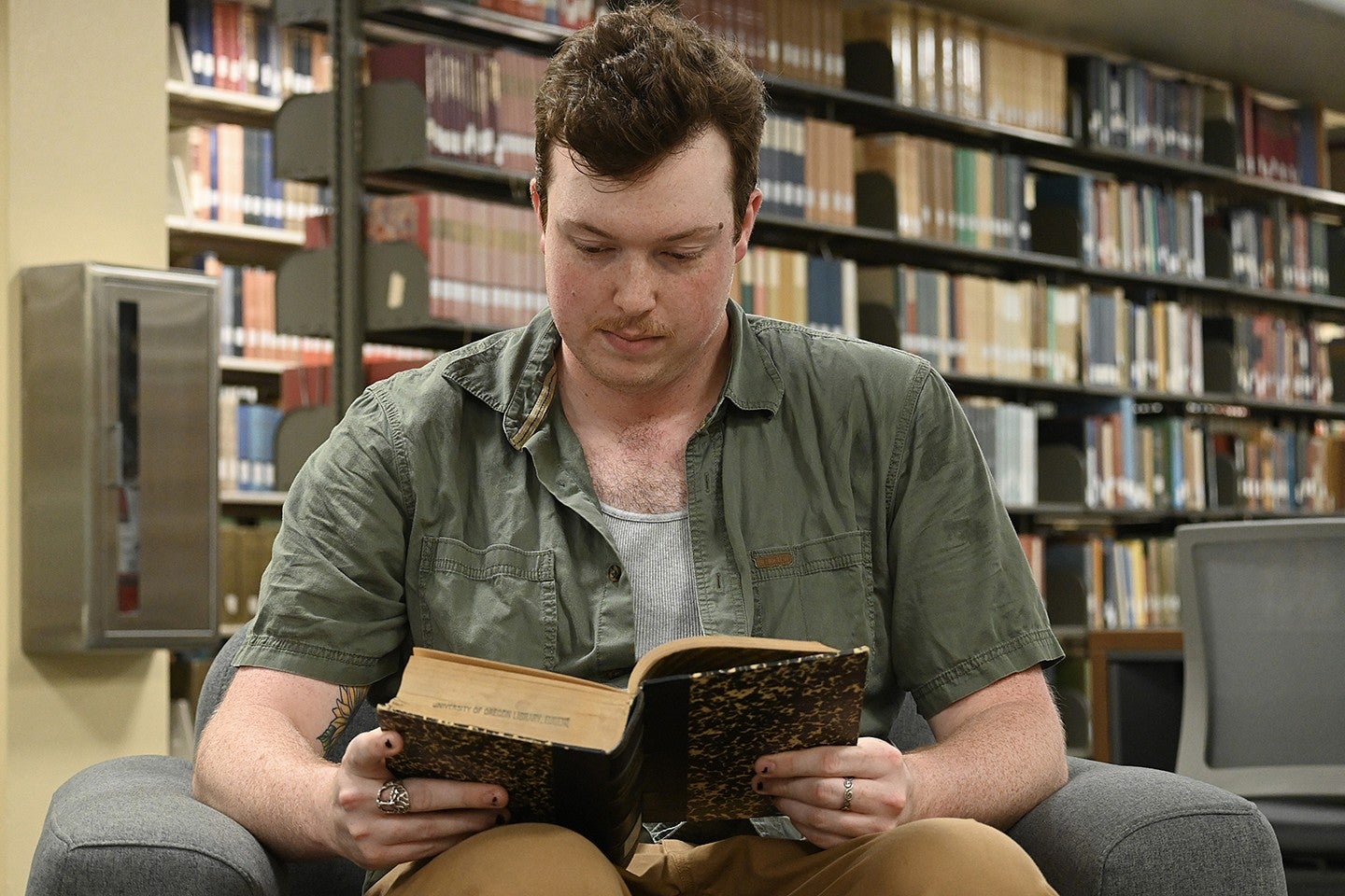 student seated in library reading old book