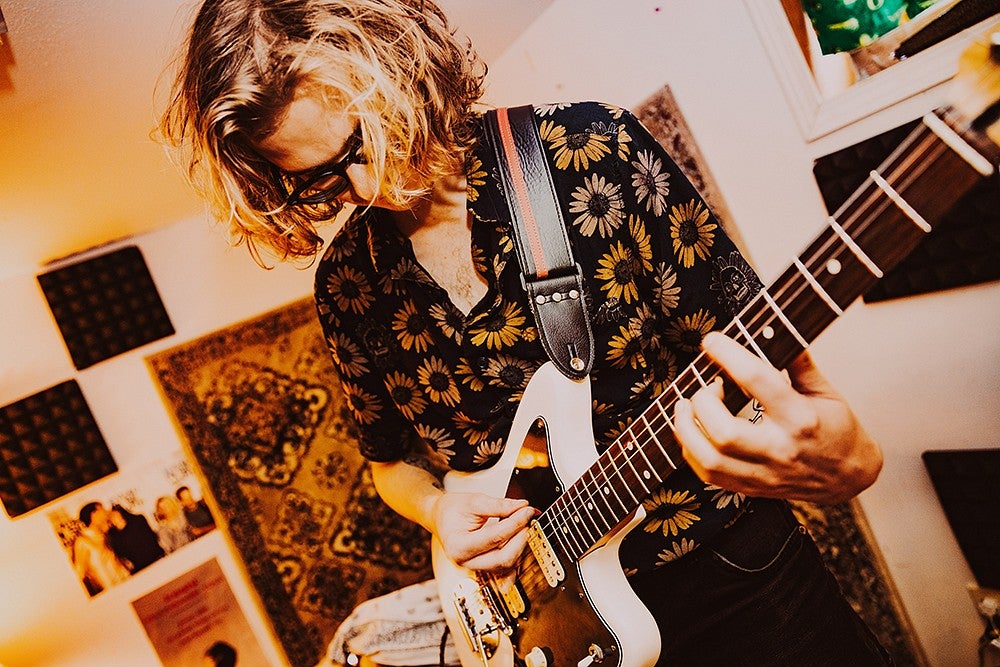 guy playing white electric guitar in small room