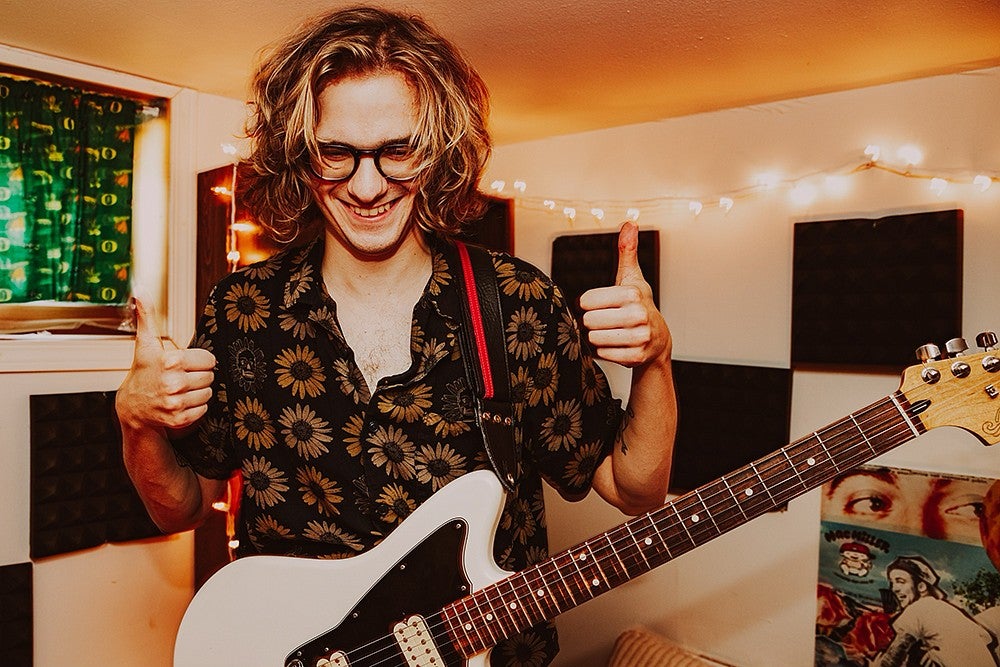 guy with white electric guitar in small rool giving thumbs up 