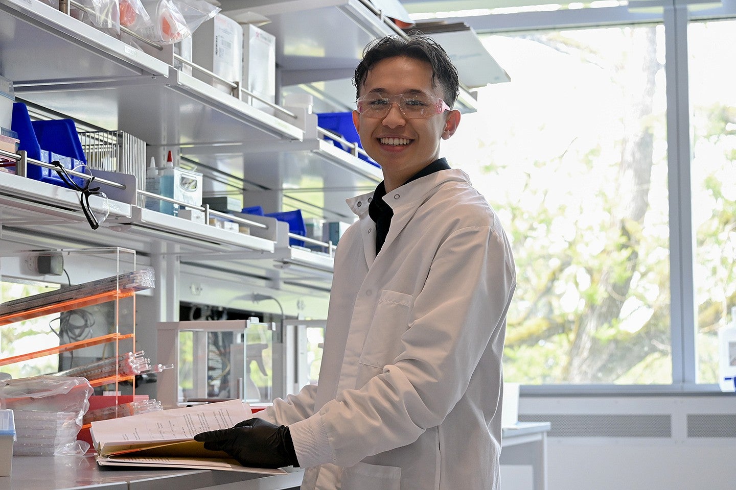 student in lab gear standing at counter in campus lab