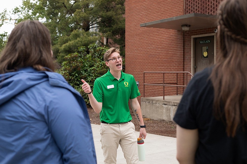 student tour guide in green shirt talking to a group and gesturing