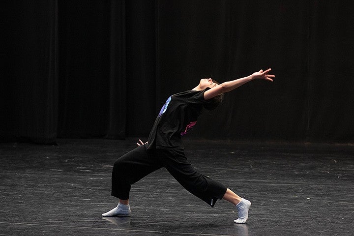 student dancing in studio with black walls and floor