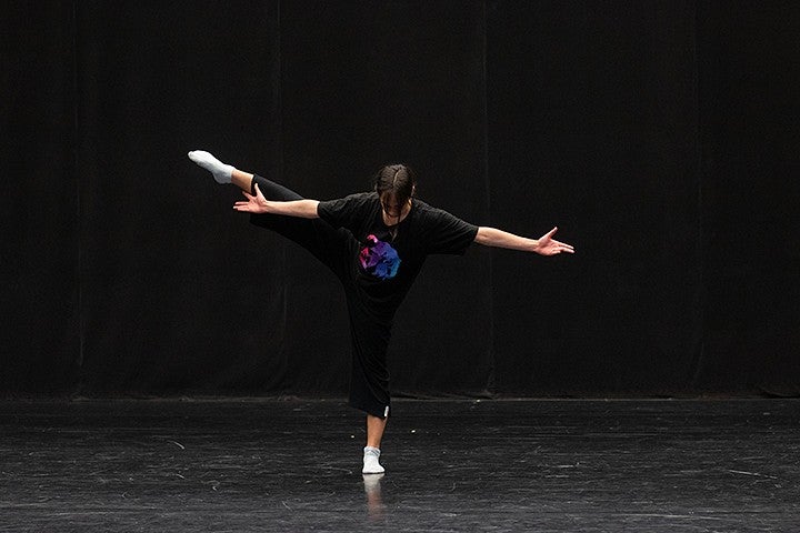 student dancing in studio with black walls and floor