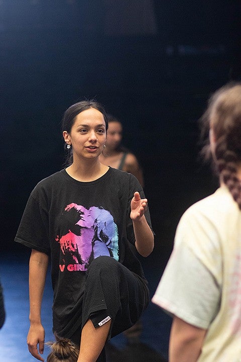 student in black dance studio talking to other dancers