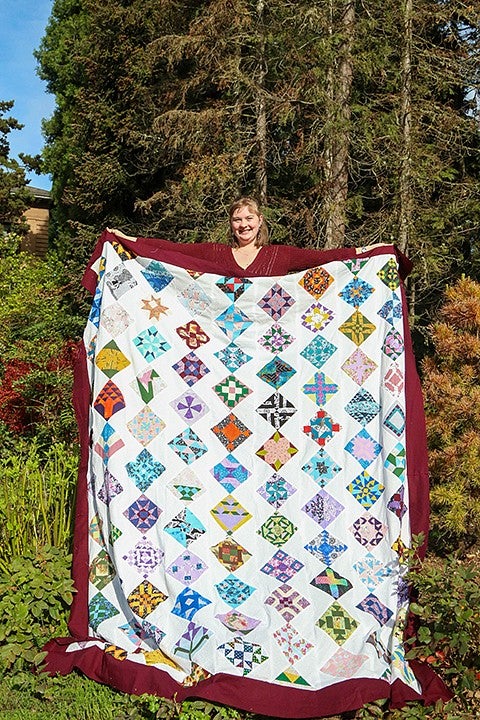 trish young outside holding up a spread-out quilt