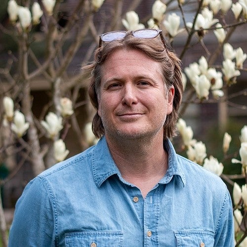 headshot of Casey Shoop with white magnolias in background