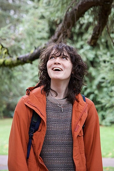 danna rubesh looking up at trees outside on campus, smiling