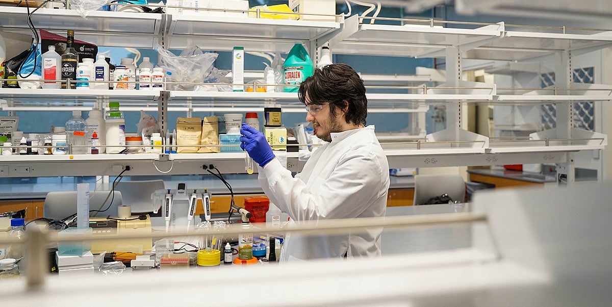 oliver loreto at a campus lab bench holding test tubes