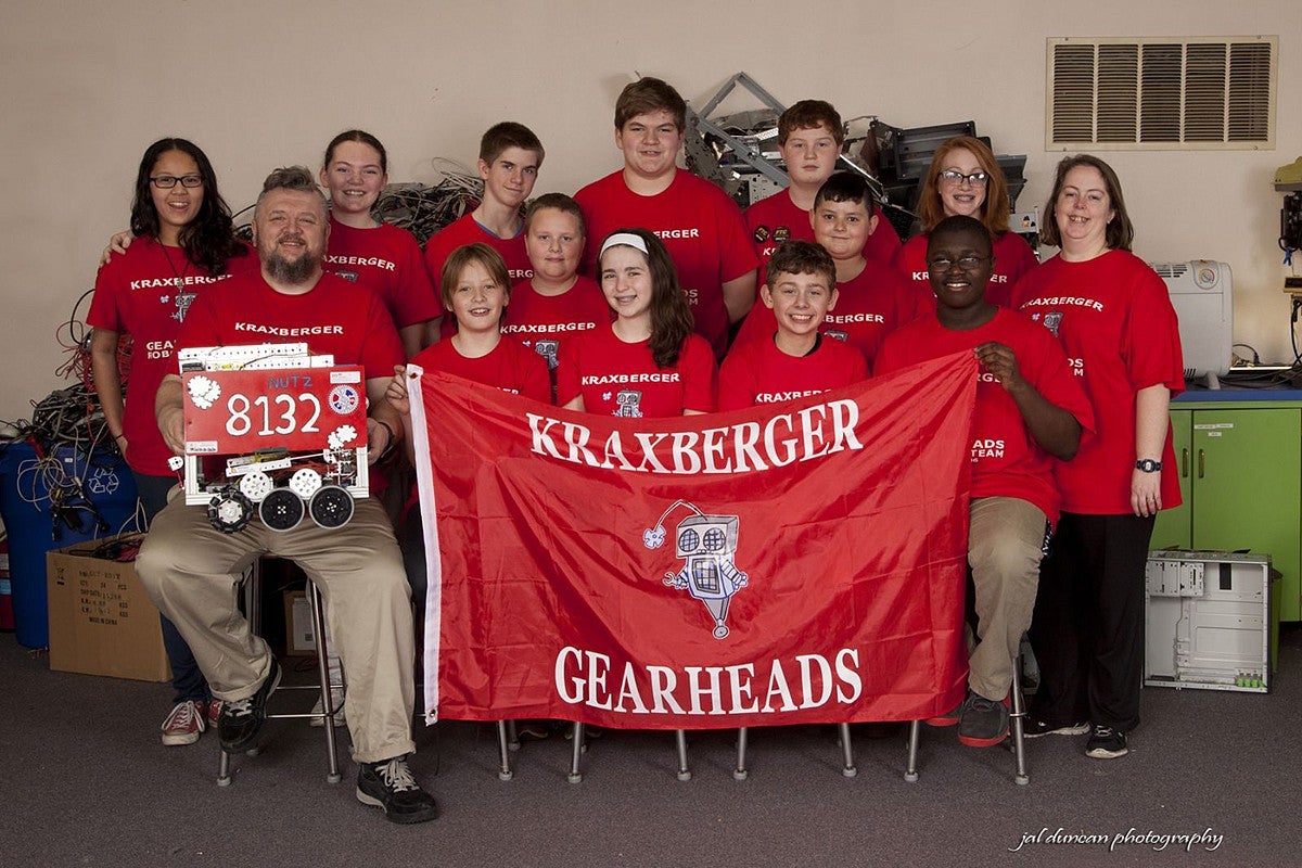 a grade school robotics club posing for a group photo holding the banner "kraxberger gearheads"