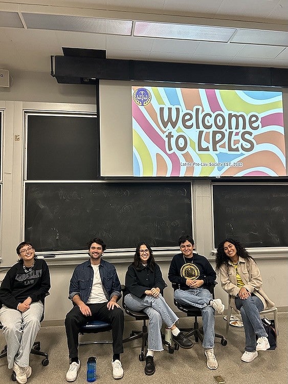 students in a classroom under an overhead projector reading "welcome to LPLS" with a colorful background