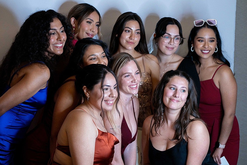 group of young women in formal dresses posing for another camera