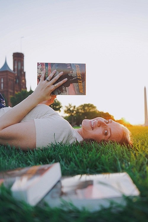 natalie jacobsen posing on grass with her forthcoming novel, Ghost Train