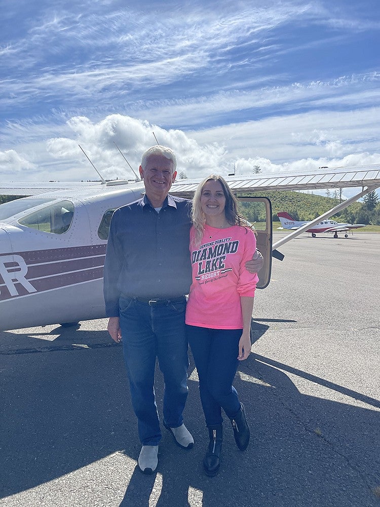 natalie jacobsen standing with her father in front of his cessna on tarmac