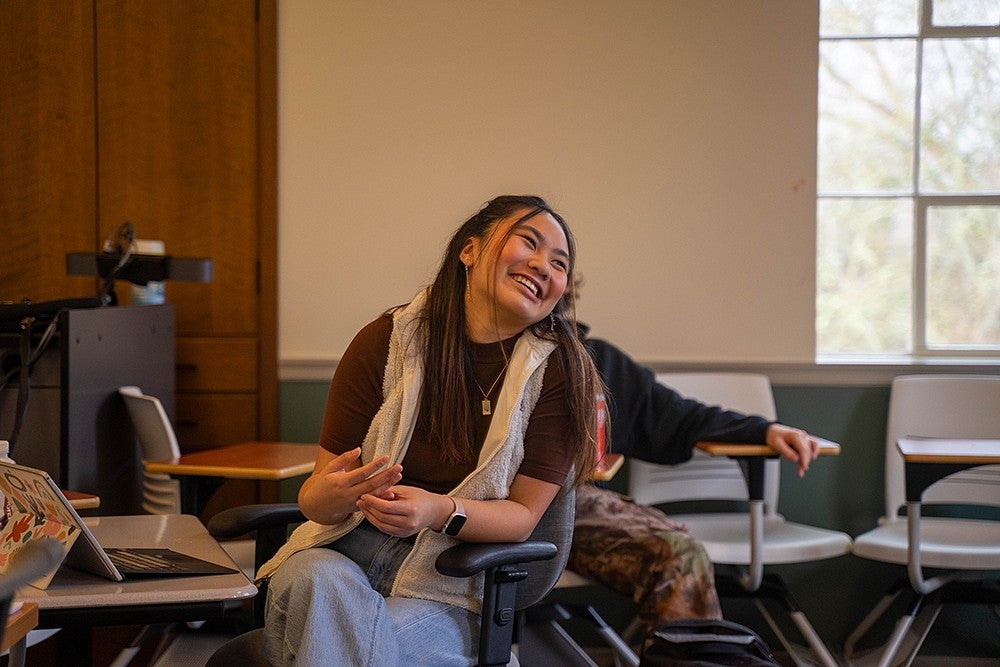 dora ho sitting in a chc classroom, smiling over her shoulder