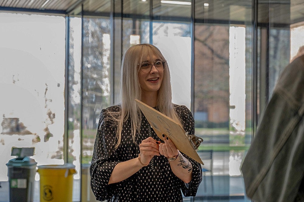 alyssa travis holding a clipboard and conversing with someone in the Tykeson hall commons