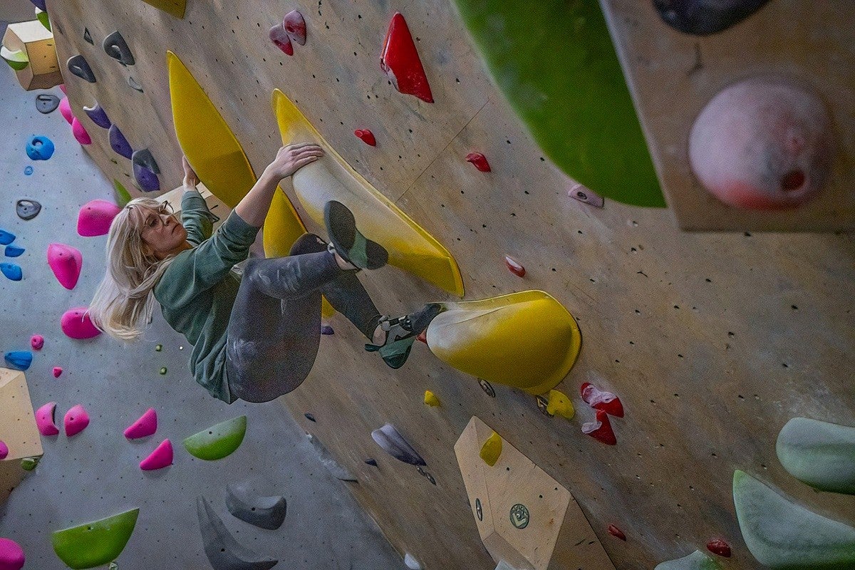 person on climbing wall overhang with colorful grips