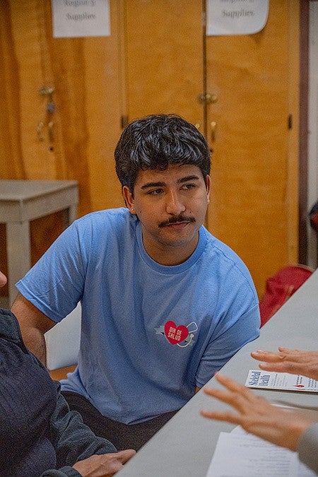 student volunteer at table listening to someone off camera