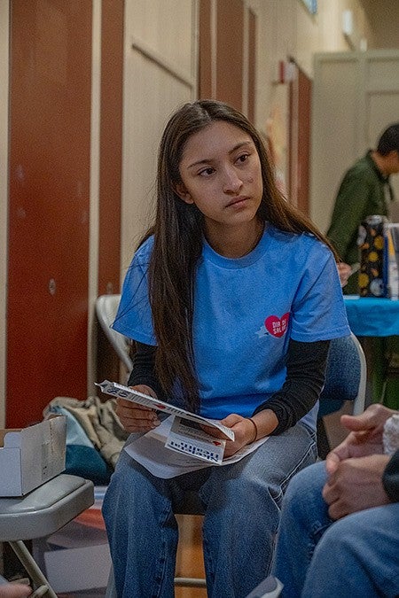 student volunteer listening with informational materials in hands
