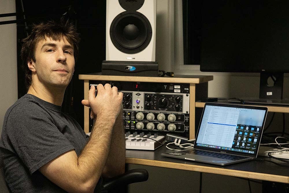 connor lowery-north seated at audio studio console with laptop