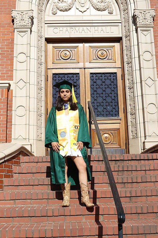 harper mcclain posing in grad regalia on chapman steps