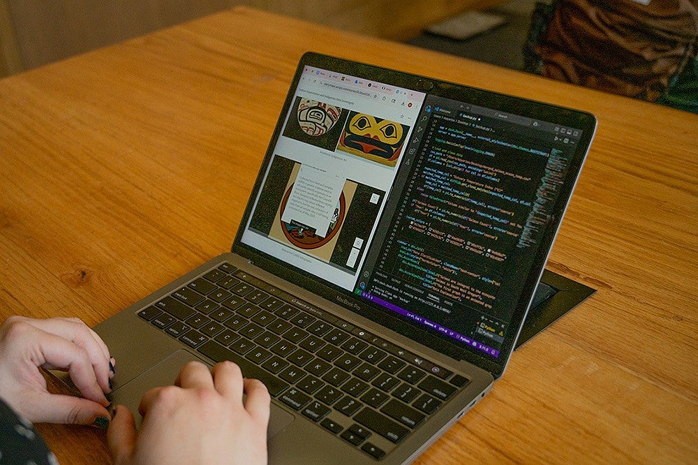 laptop showing code and indigenous art