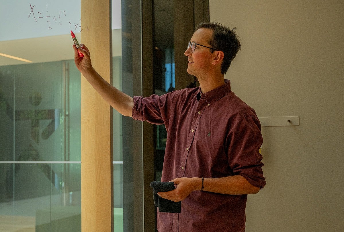 student writing equation on glass with marker