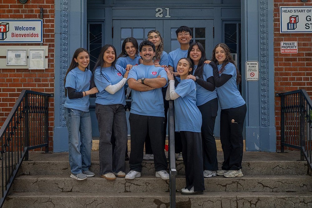 group of student volunteers posing on steps of school