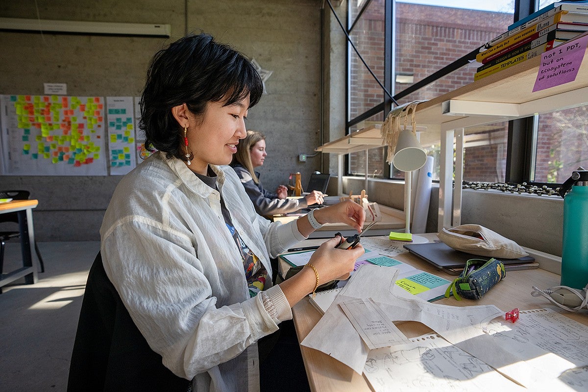 student at studio desk, cutting materials