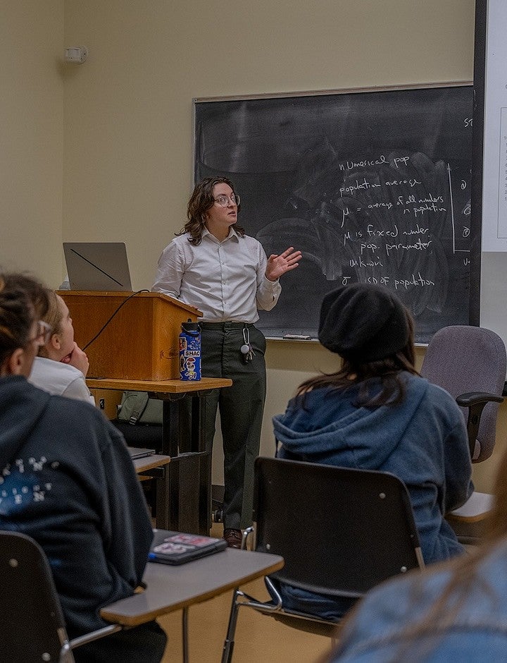 student giving presentation from front of classroom