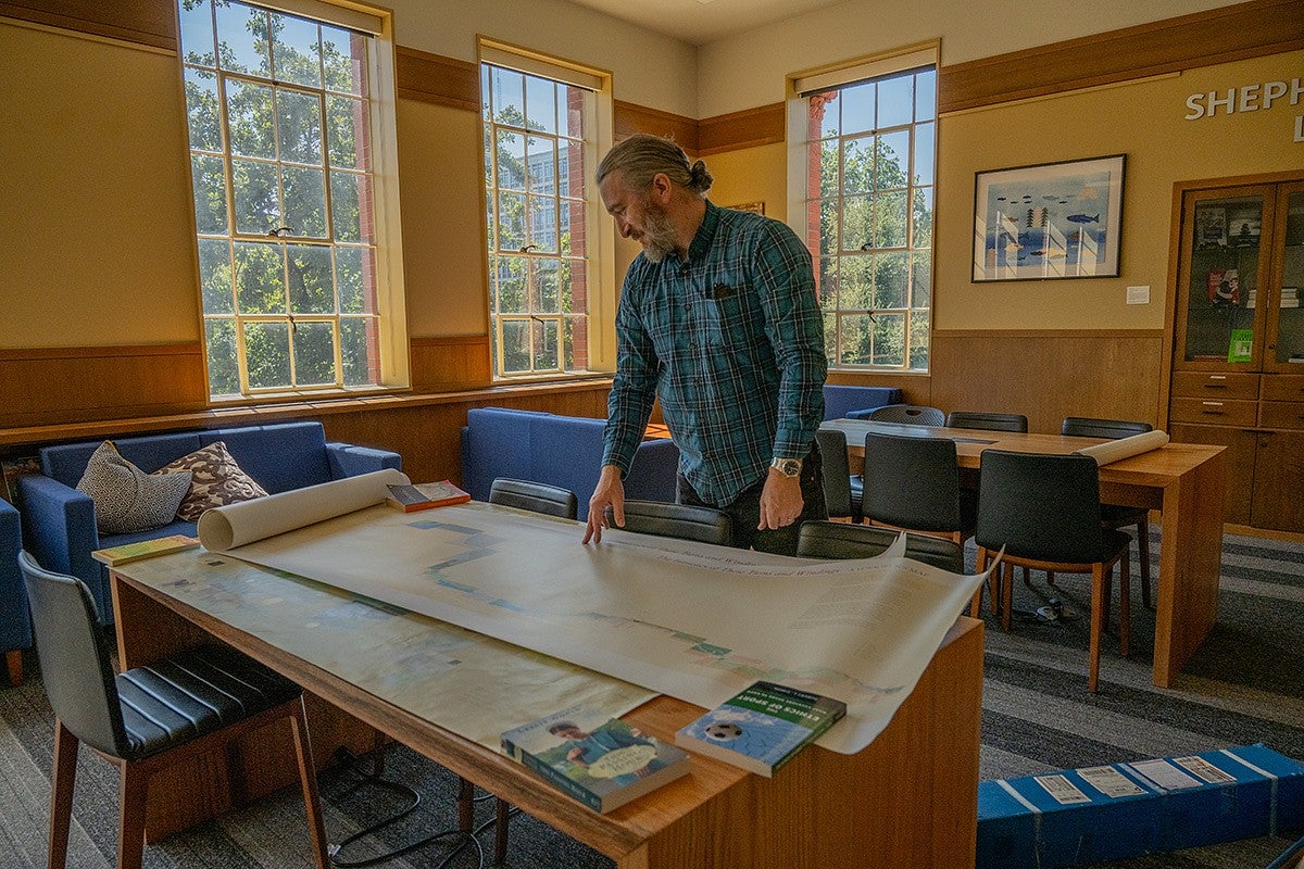 Marcel Brousseau standing over a table of large maps in the Chapman Hall Library