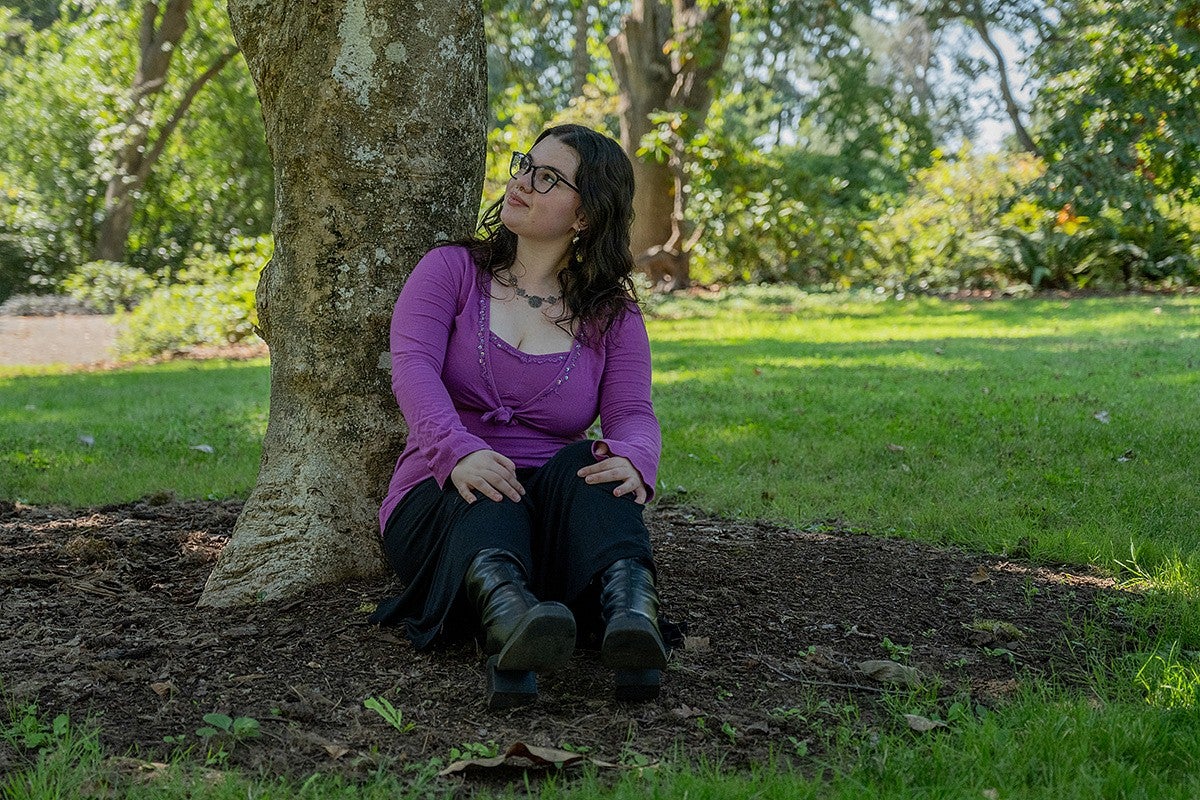 sierra matz seated against a tree trunk in a park