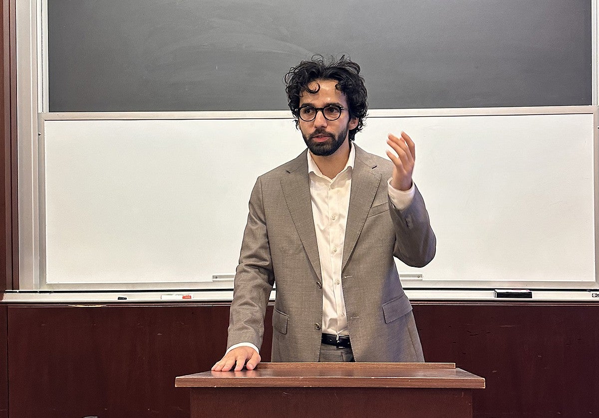 parsa aghel standing at a lecture hall podium, speaking and gesturing