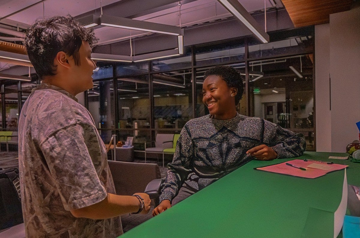 two students talking at table in campus building