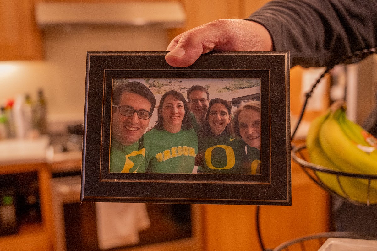 hand holding framed photo of fred, alex and joy poust posing with two other people in duck gear