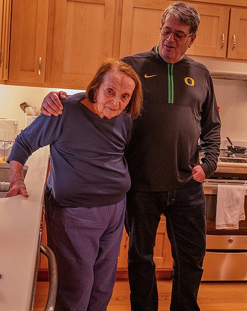 fred poust with his arm around his mother joy in a kitchen