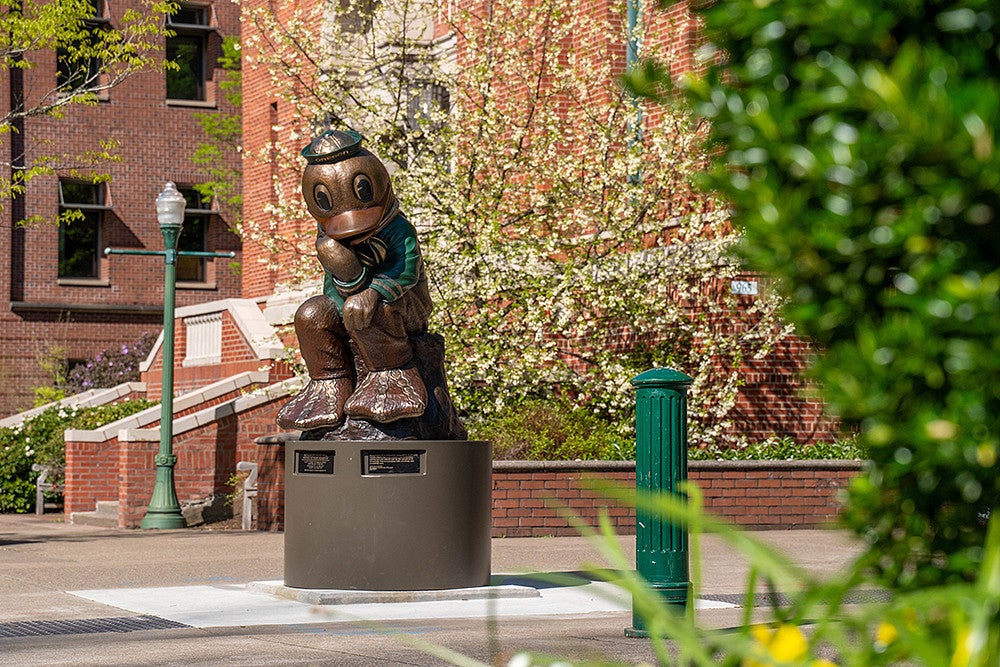 thinker duck statue with spring blossoms