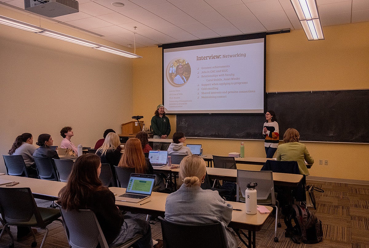 classroom of students watching two students present slides