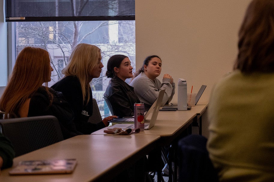 students sitting in a class, one talking toward front of room