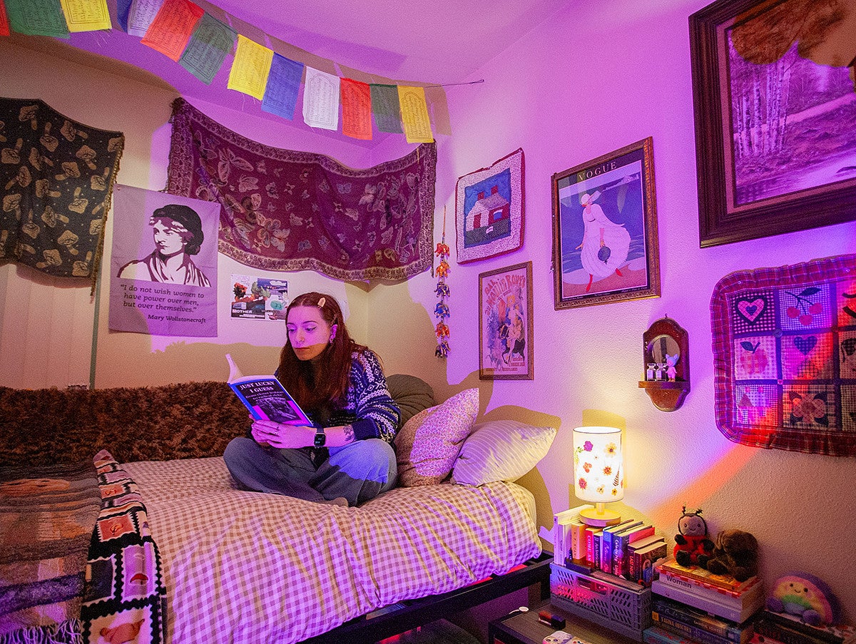 avery suriano sitting on bed reading, surrounded by art, books and her belongings
