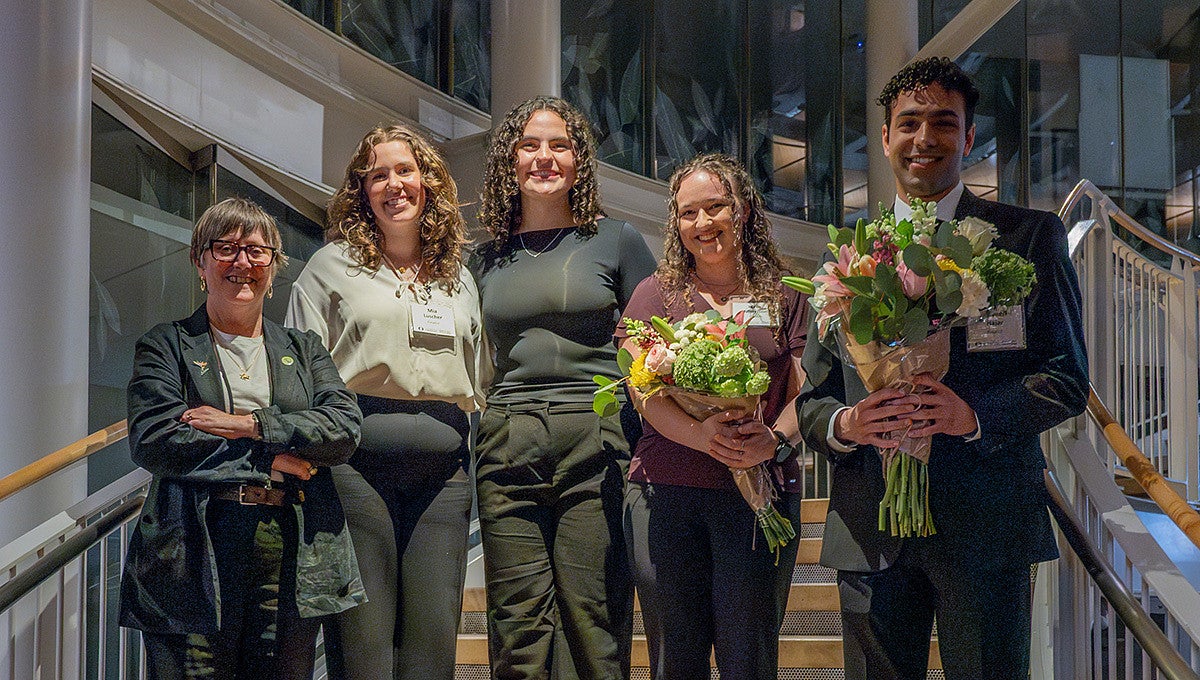 four winners of the 2026 three minute thesis competition posing with dean carol stabile and bouquets