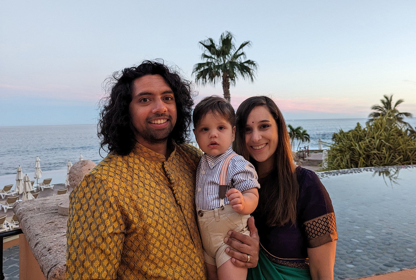 couple with small child posing at twilight with ocean