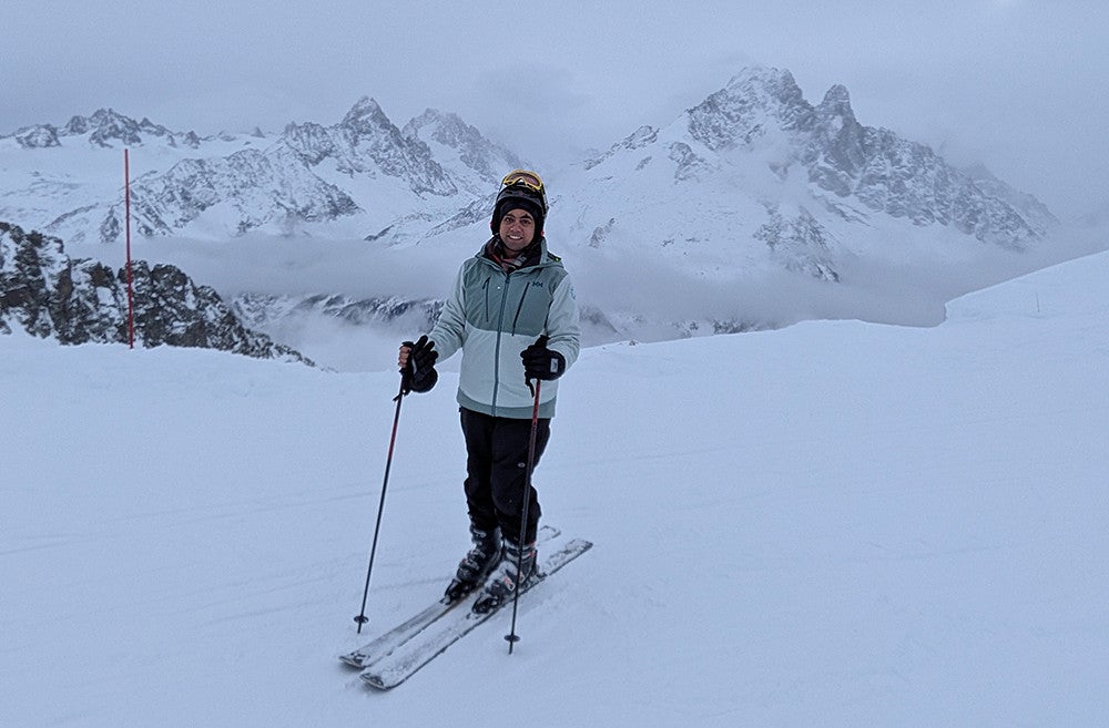 person on skis posing on ski slope with snowcovered mountains in background