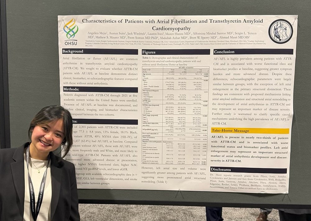 person in business casual at a conference standing in front of a research poster on cardiology