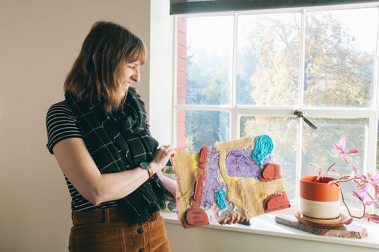 kristen rahilly in her office, looking at an artistic map made by a student