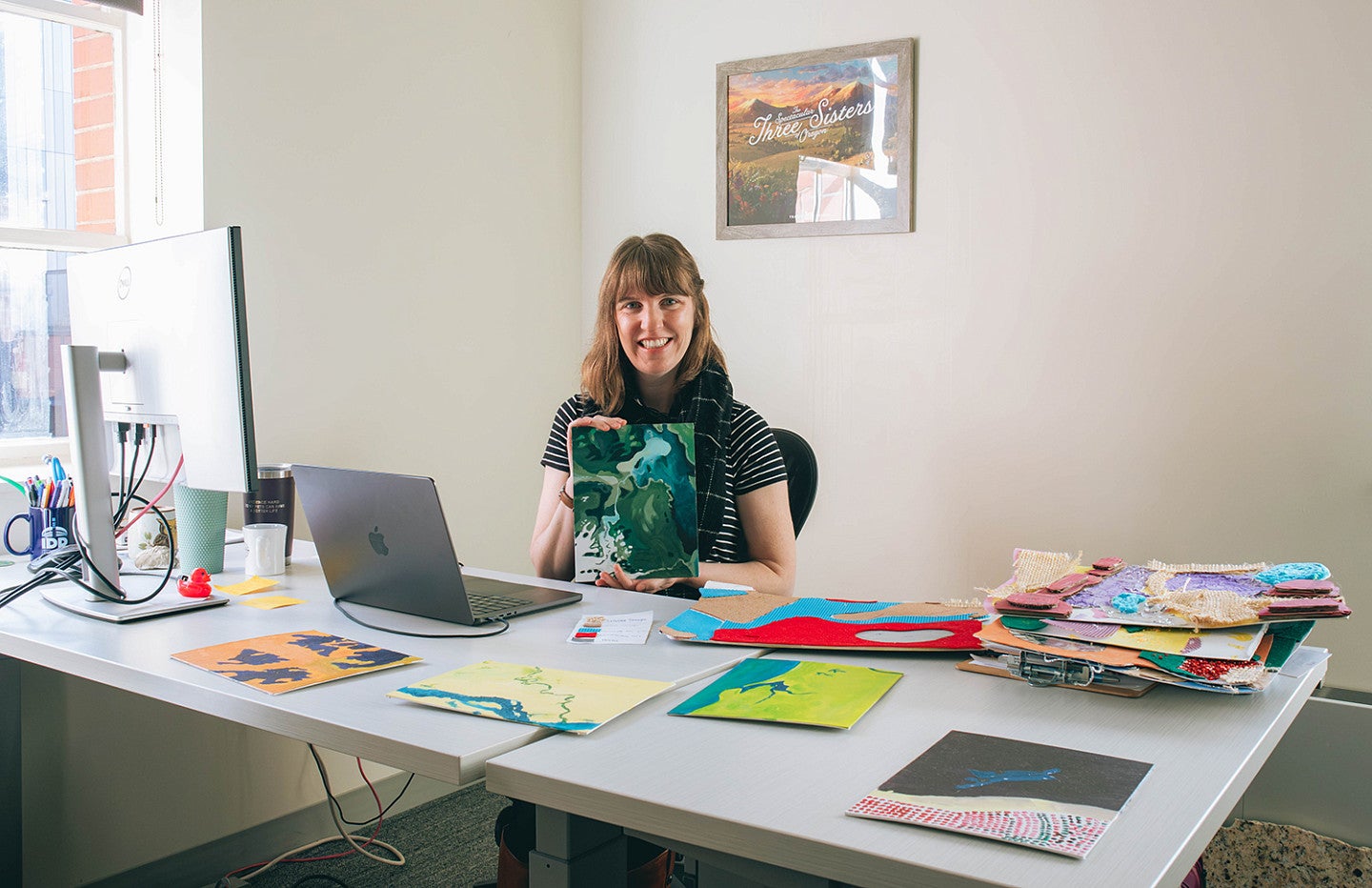 kristen rahilly at her office desk surrounded by abstract student art
