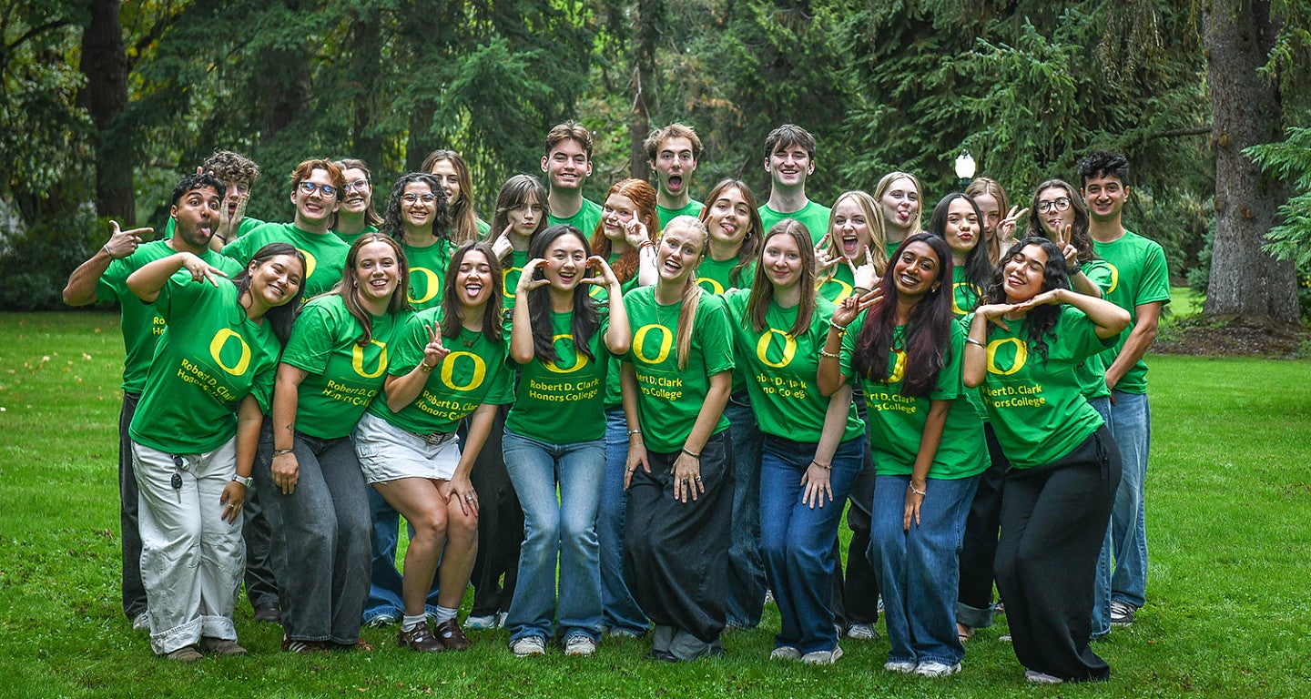 group of chc peer mentors in green tshirts posing with silly faces on campus green space